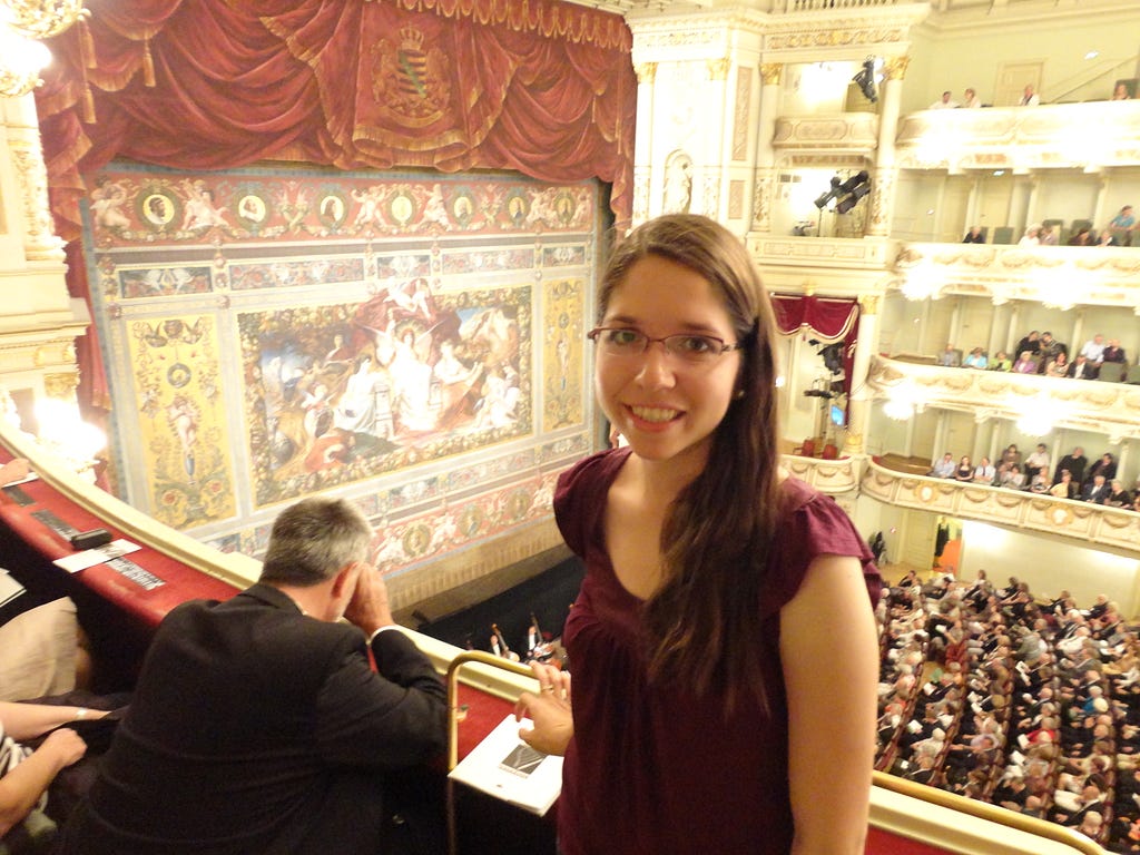 The author stands by a balcony in an opera theatre.