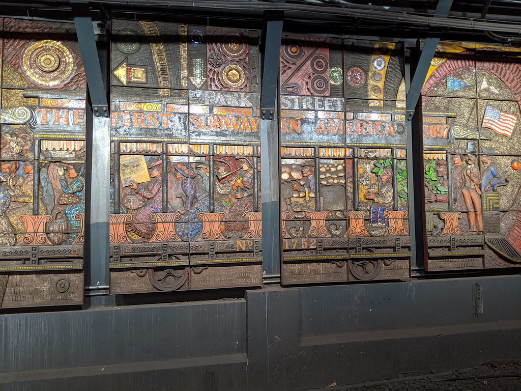 Multi panel mosaic of a trolley filled with passengers for the first subway ride in America on 9/1/1897 on on a station wall