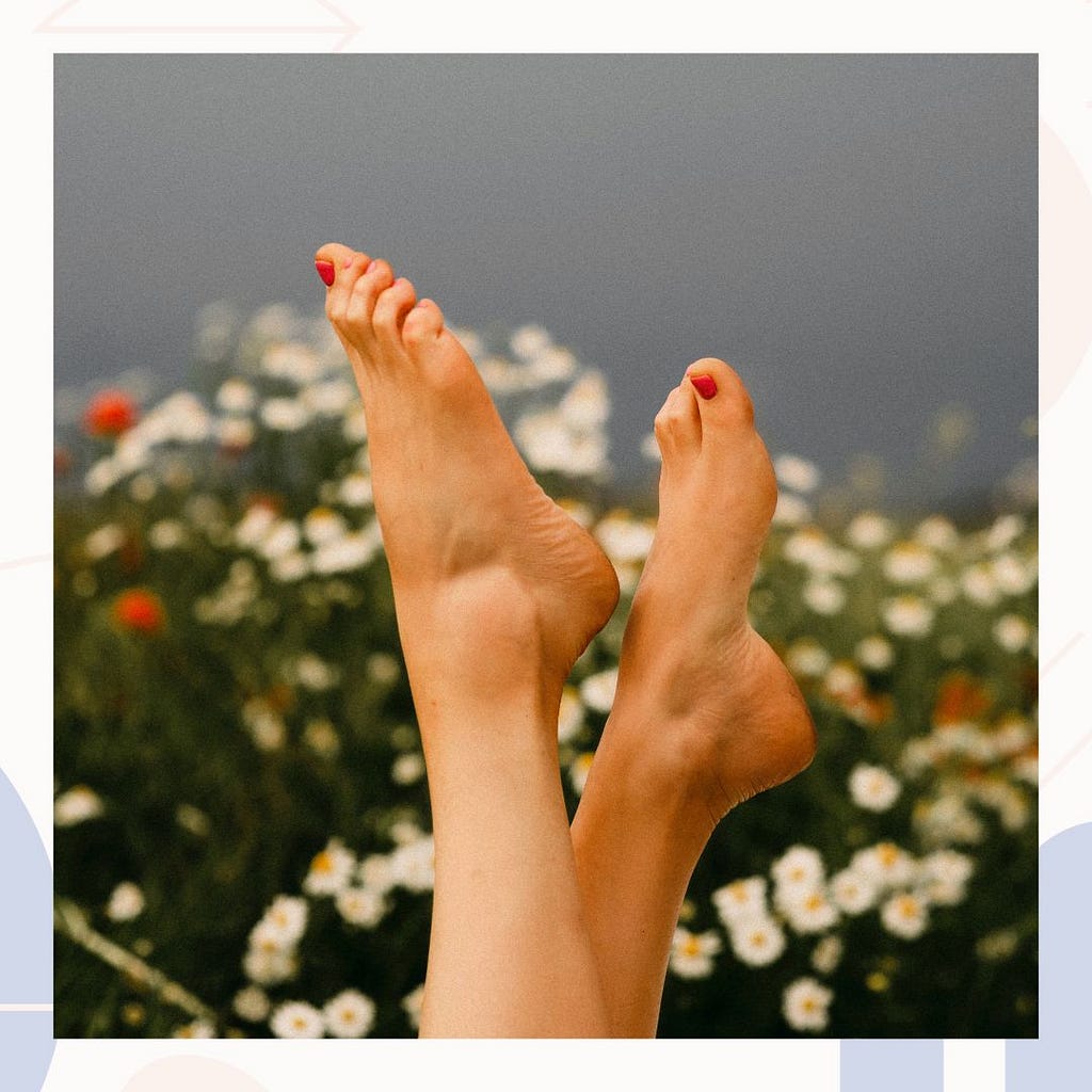 Lady’s feet with red toenail polish pointed toward the sky with a floral background