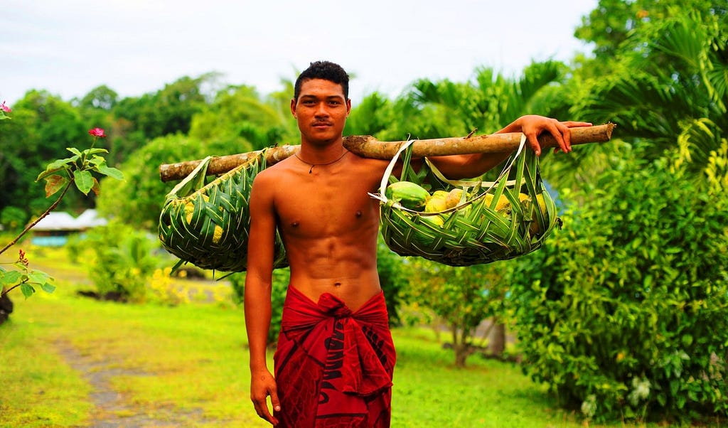A Samoan young man with a piece of ‘skirt’ and carrying fruits.