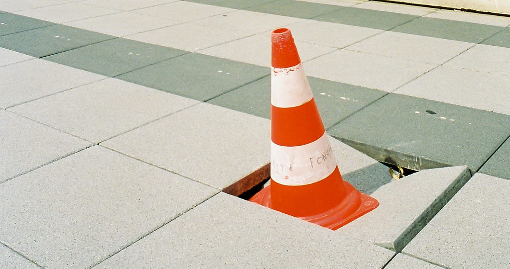 Traffic cone stuck in broken concrete tile.