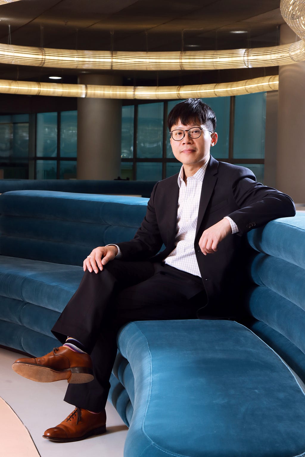 Professor Michael Huen Shing-yan sitting on a blue sofa at HKUMed looking straight at the camera with his legs crossed.