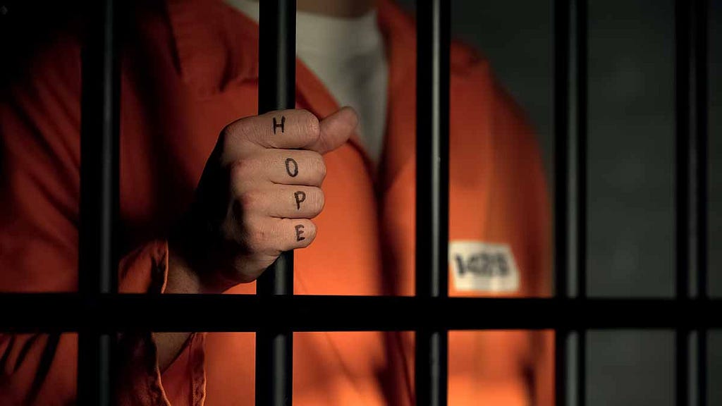 man in jail with hope written on hand