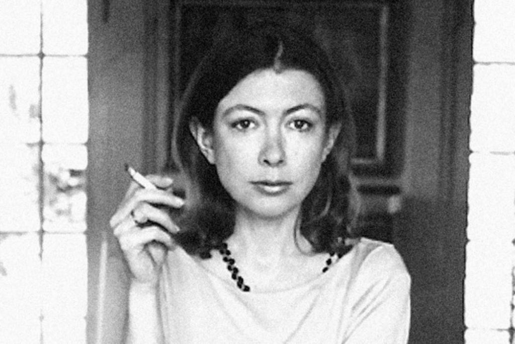 Black and white image of Joan Didion at her home in Hollywood in 1970, staring into the camera and holding a cigarette.