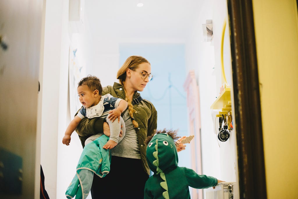 Mother with children standing by door at home.