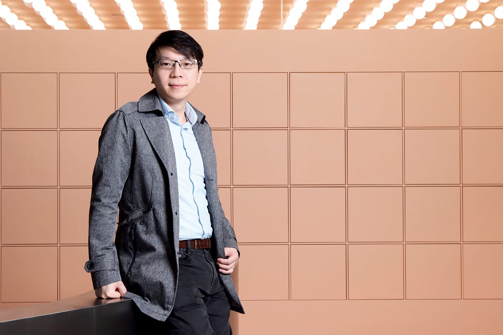 Dr Tommy Lam Tsan-yuk  from the University of Hong Kong stands in front of a nude squared wall.
