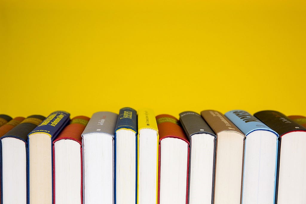 An image of books turned on their sides against a bright yellow background.