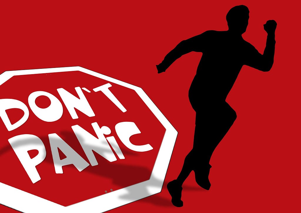 Silhouette of a man running with a white “don’t panic” sign.