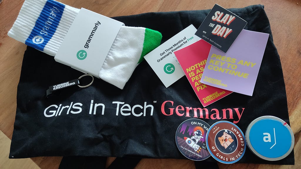 The contents of my Girls in Tech Goodie Bag: Grammarly free subscription, socks, stickers and bottle opener from sponsors.