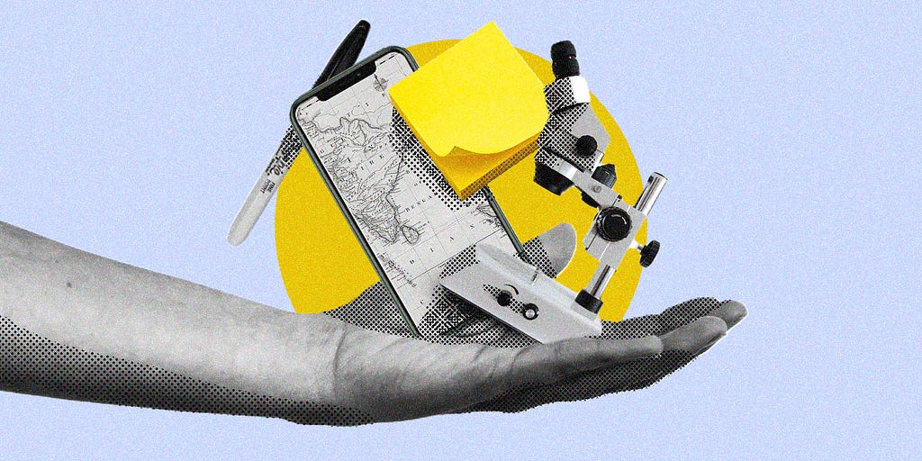 Open hand facing upwards holding a mobile phone, microscope, post-it notes and a marker