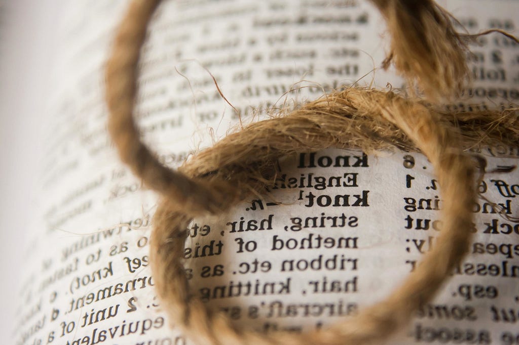 A length of twine tied into a knot sitting on top of an open book