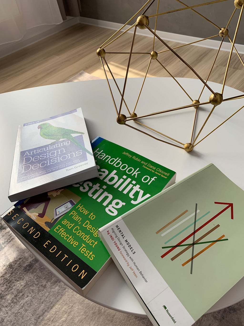 The three favourite books of Andrei on a white table in a living room. A gold geometric structure is on the table too.