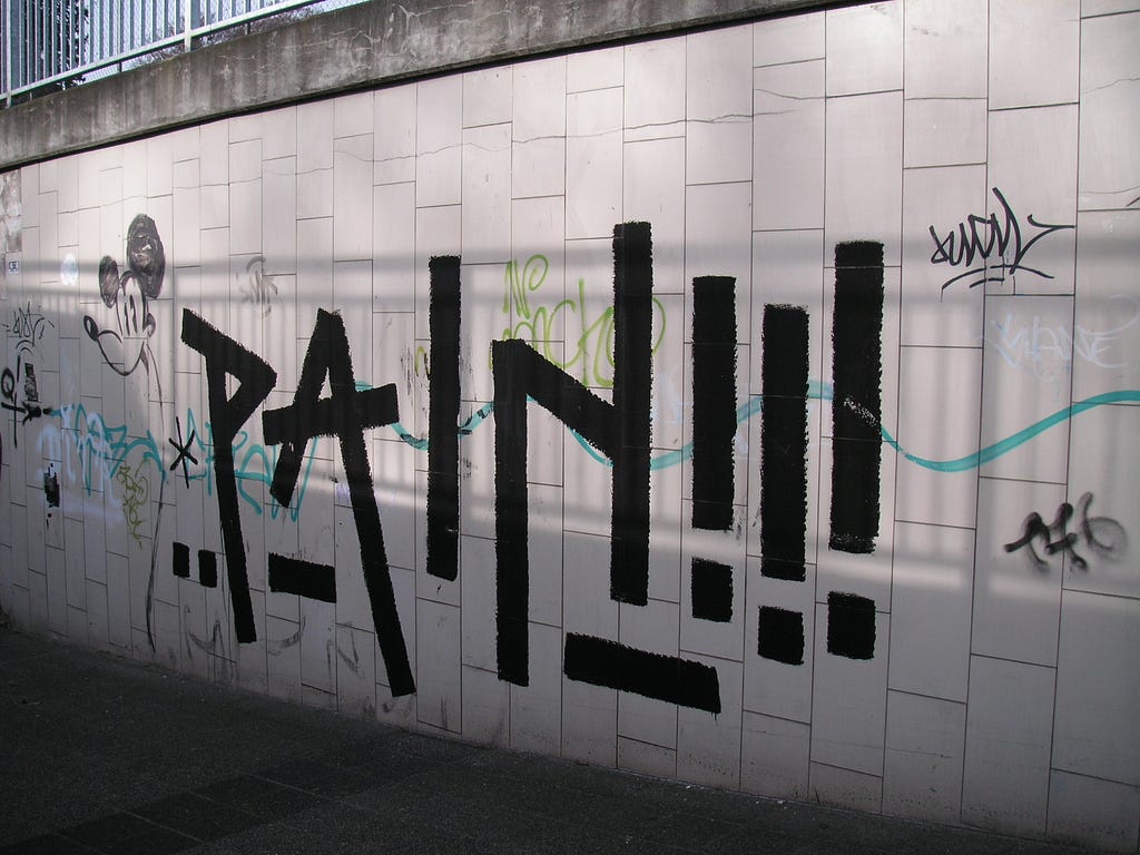 Pain, spray painted as graffiti on a wall