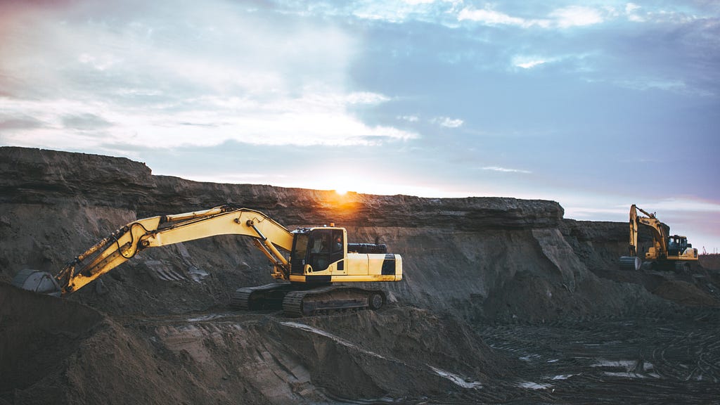 Excavators digging at a mining site at sunrise