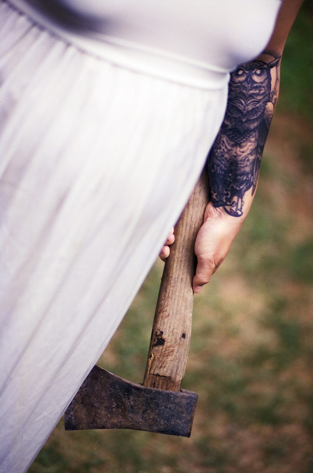 Woman wearing white shirt and holding an axe.