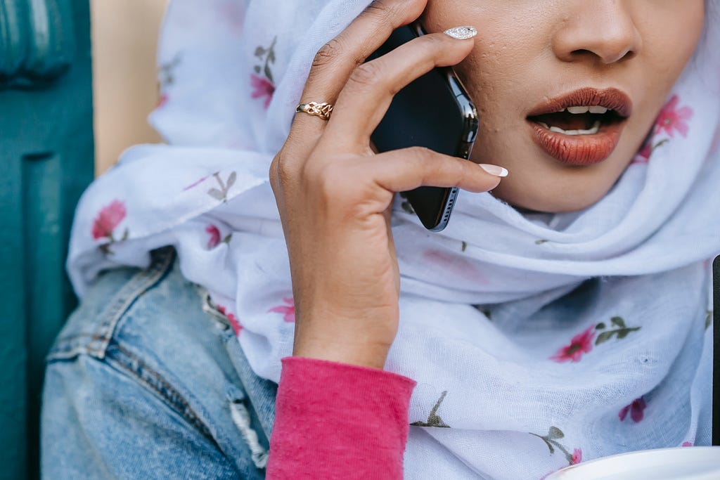 A closeup of a woman holding her phone with her mouth opened.