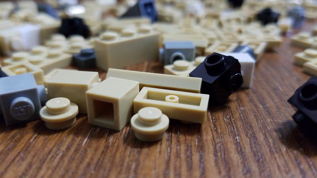 A public domain image of small lego pieces laying across a hardwood floor