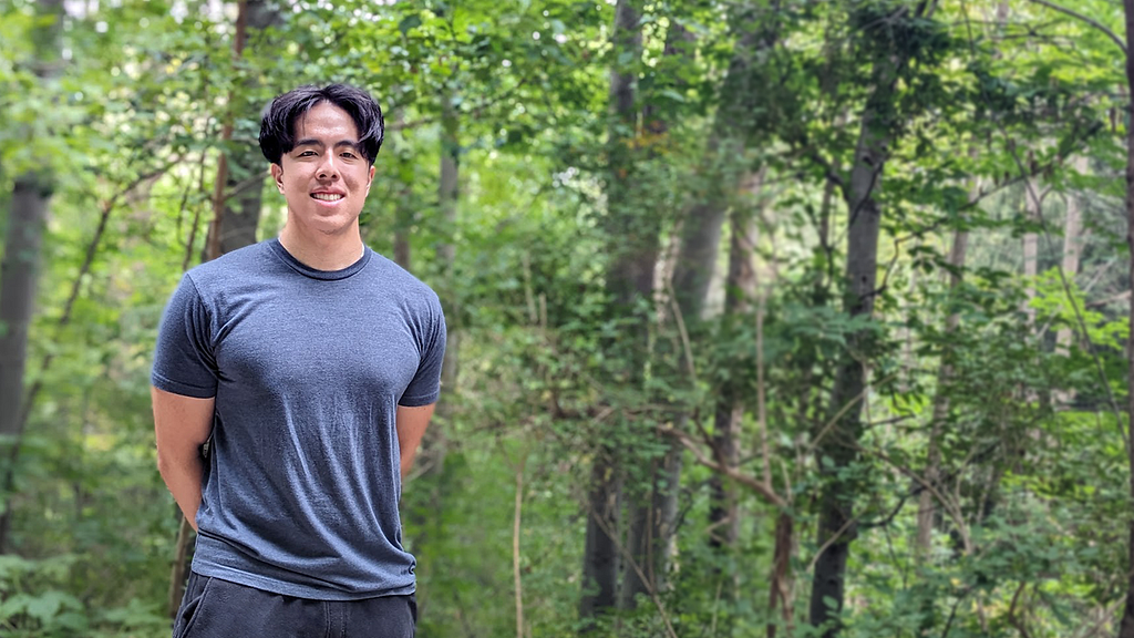 Author standing in front of forestry background smiling at camera