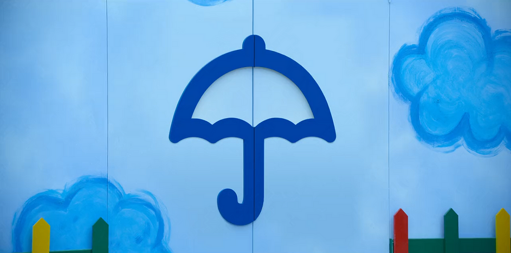 contorno de guarda chuva azul colado em uma parede azul claro com desenhos de nuvens