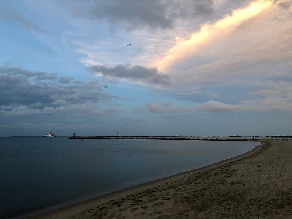A picture of the Delaware Bay from Lewes Beach at sunset as two birds swoop over the bay.