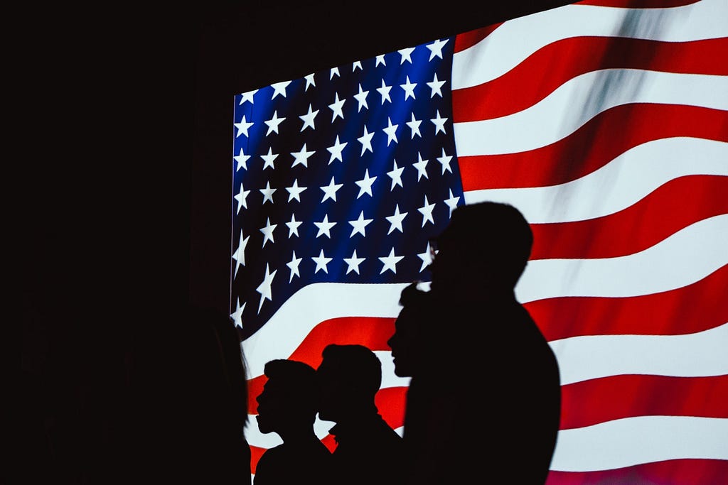 Silhouettes of people in front of the American flag
