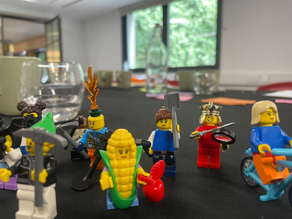 Photo shows oddly dressed lego charactors on a boardroom table in front of a sunny window.