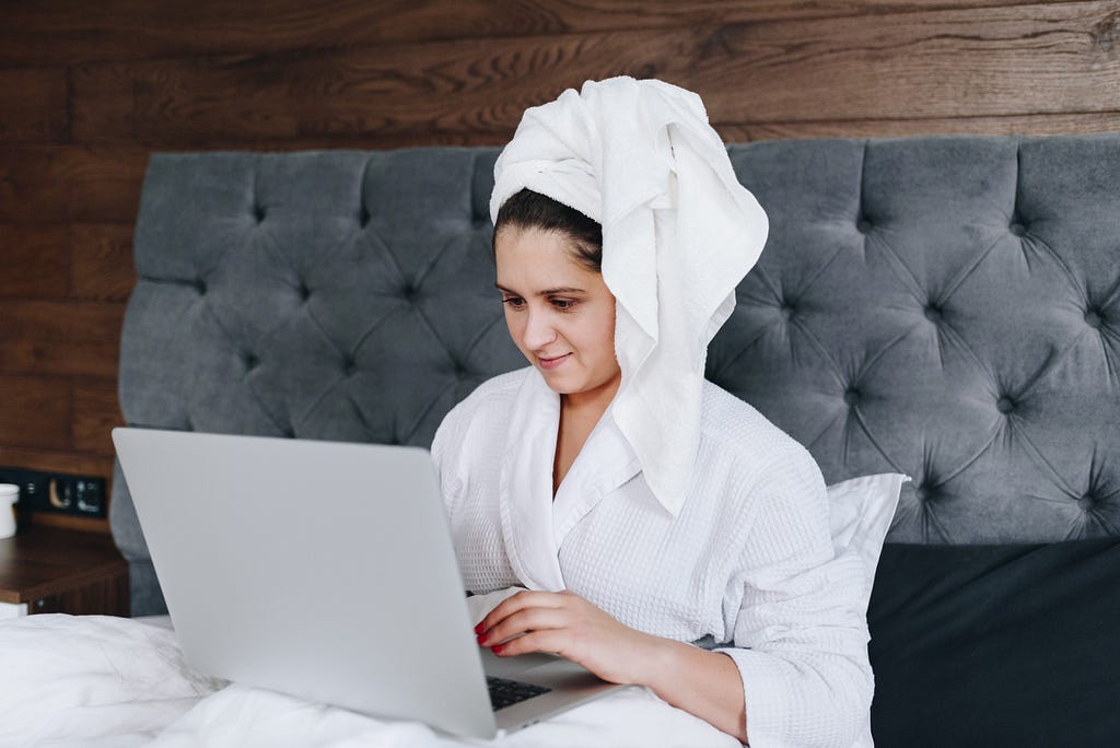 A woman working on her bed right after she has had a shower.