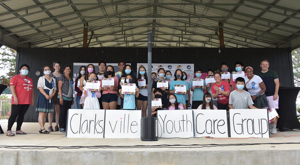The Clarksville Youth Care Group stands on a short stage, displaying their products.