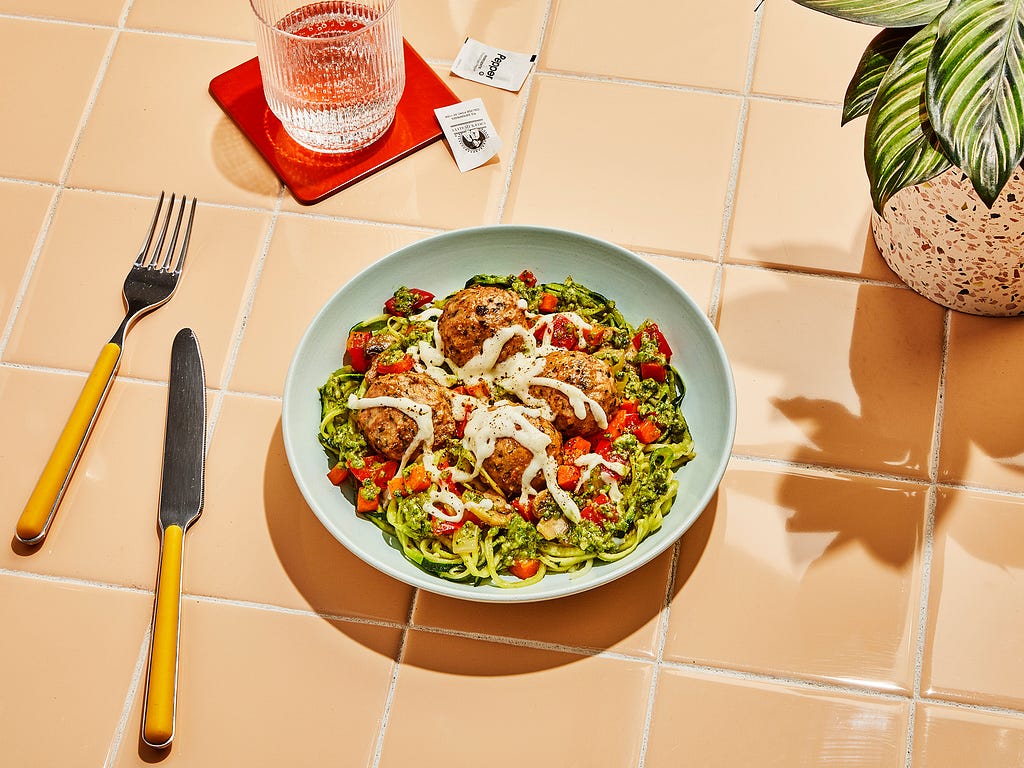 Meatballs on zucchini noodles on a tiled table