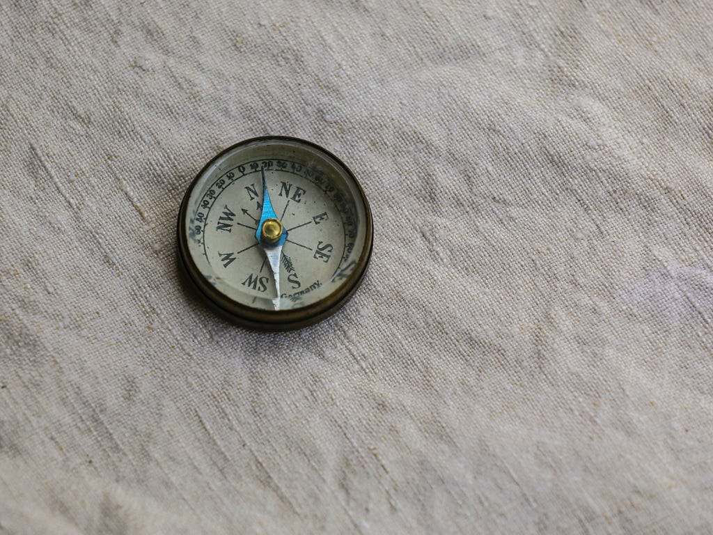 An old-fashioned compass lying on a piece of linen
