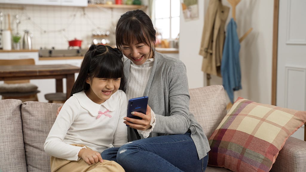 Mother and daughter interacting with a mobile phone together
