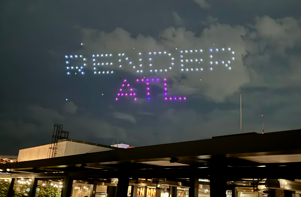 A drone show spelling the words “Render ATL” in the night sky overlooking an outdoor viewing area.