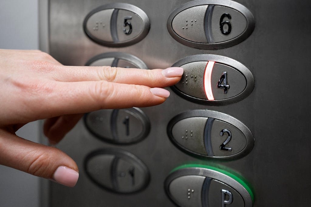 Blind person pressing the lift button in Braille.