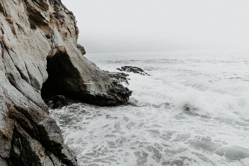 Ocean waves crashing into a rocky coast and cave.