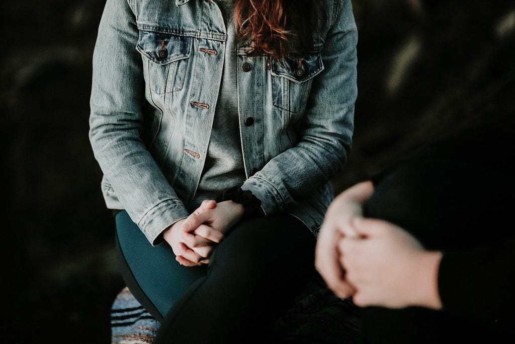 two people sitting across each other with hands folded in their lap