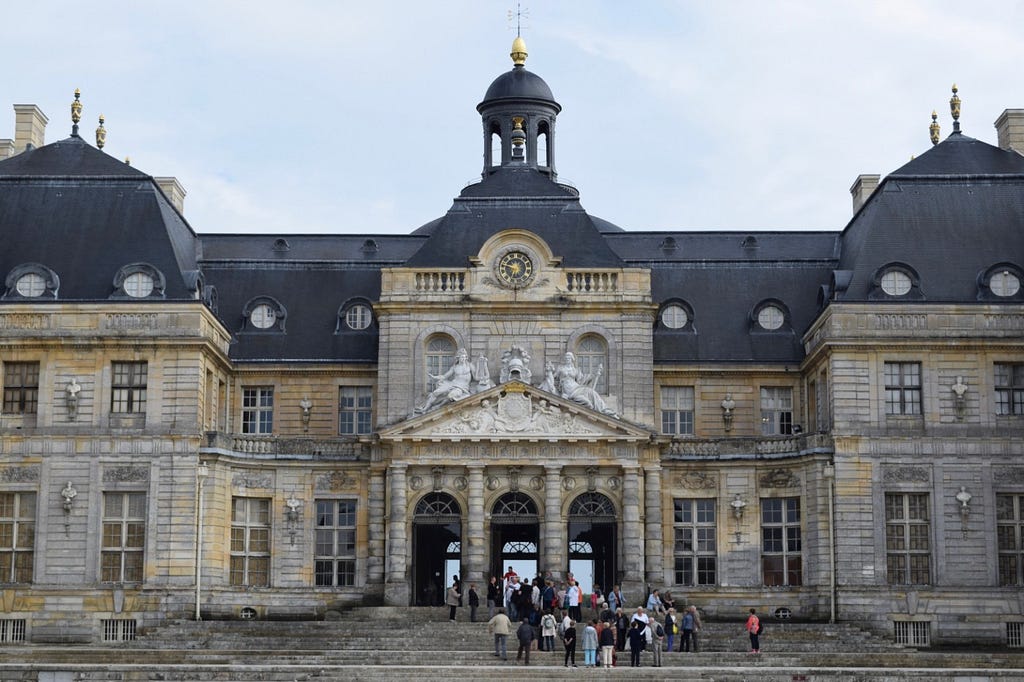 A tour group pauses on the front stairs of the Château de Vaux-le-Vicomte.