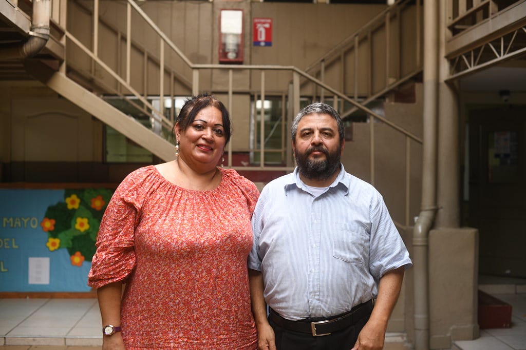 Gabriela and Jose Angel stand facing the camera in the school where she studied.