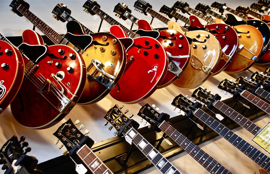 Imagem mostrando uma série de guitarras à mostra em uma loja de instrumentos musicais
