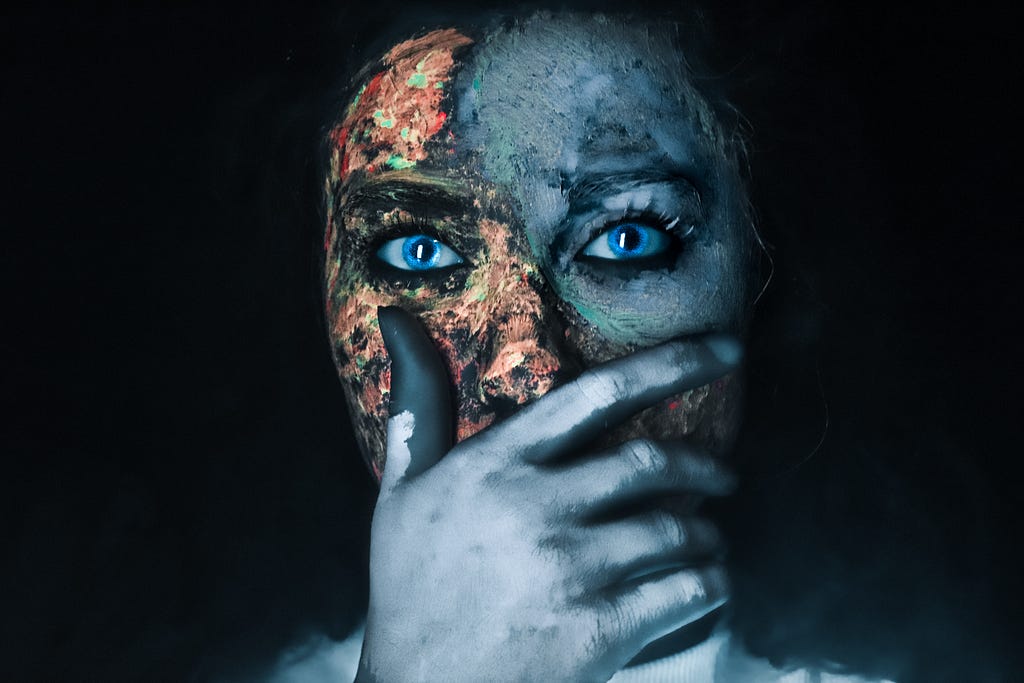 Woman with face-paint looking into the camera in front of a black background