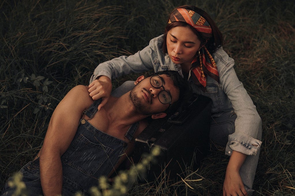 a man and a woman lay together in the grass