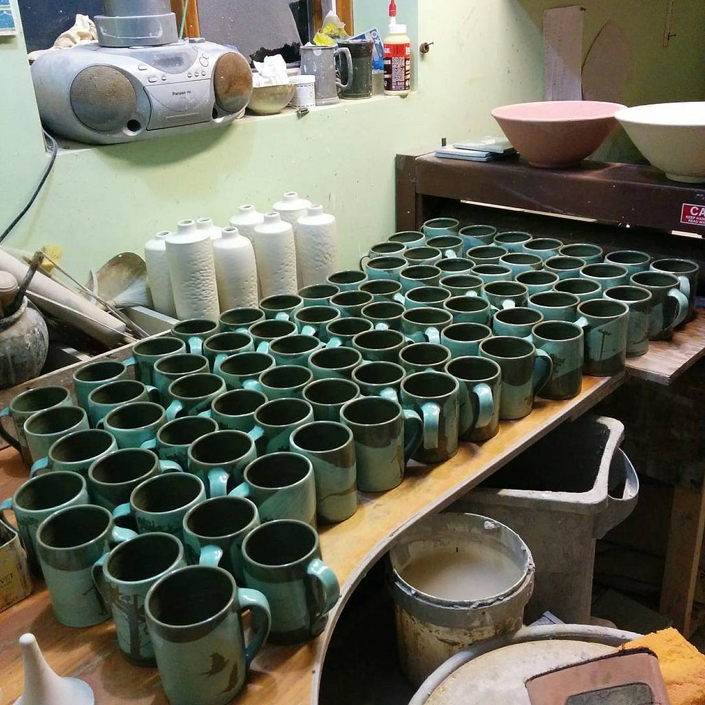 a set of teal mugs in a pottery studio