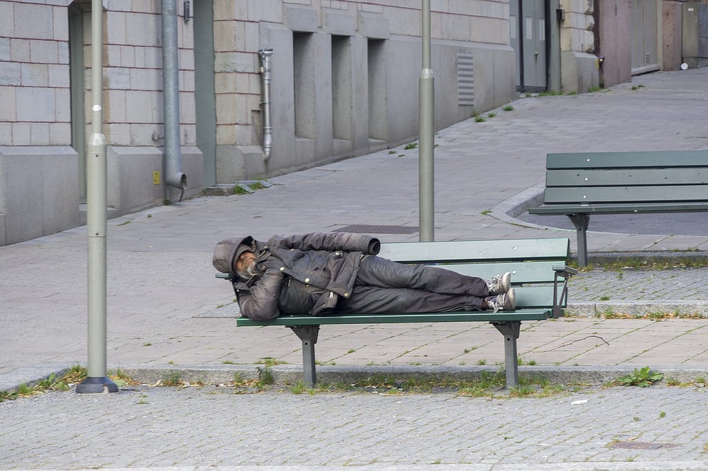 Homeless man sleeping on a public bench