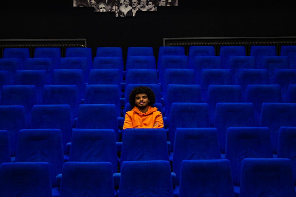 Marius GIRE took this photo of a man in an orange hoodie sitting alone in an empty movie theater.