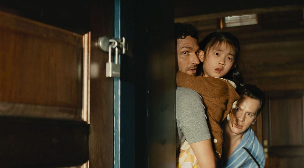 photo of a frightened Eric and Andrew holding their daughter and looking around a corner