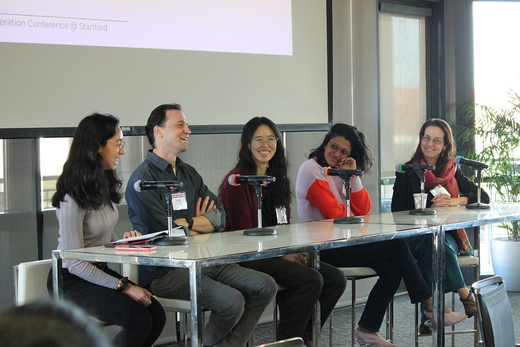 Veronica Rivera, Michael Bernstein, Amy Zhang, Deepti Doshi, and Susan Benesch sitting at a table smiling and laughing.