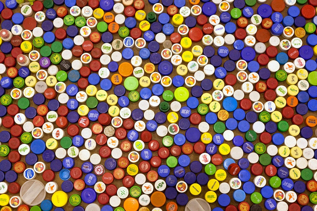 A view from above of a large quantity of bottle caps of different colors places very close to each other