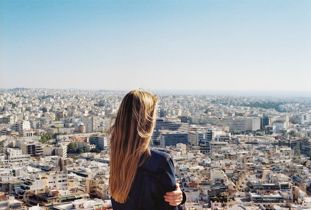 Woman from high vantage point looking out over a densely populated Greece.