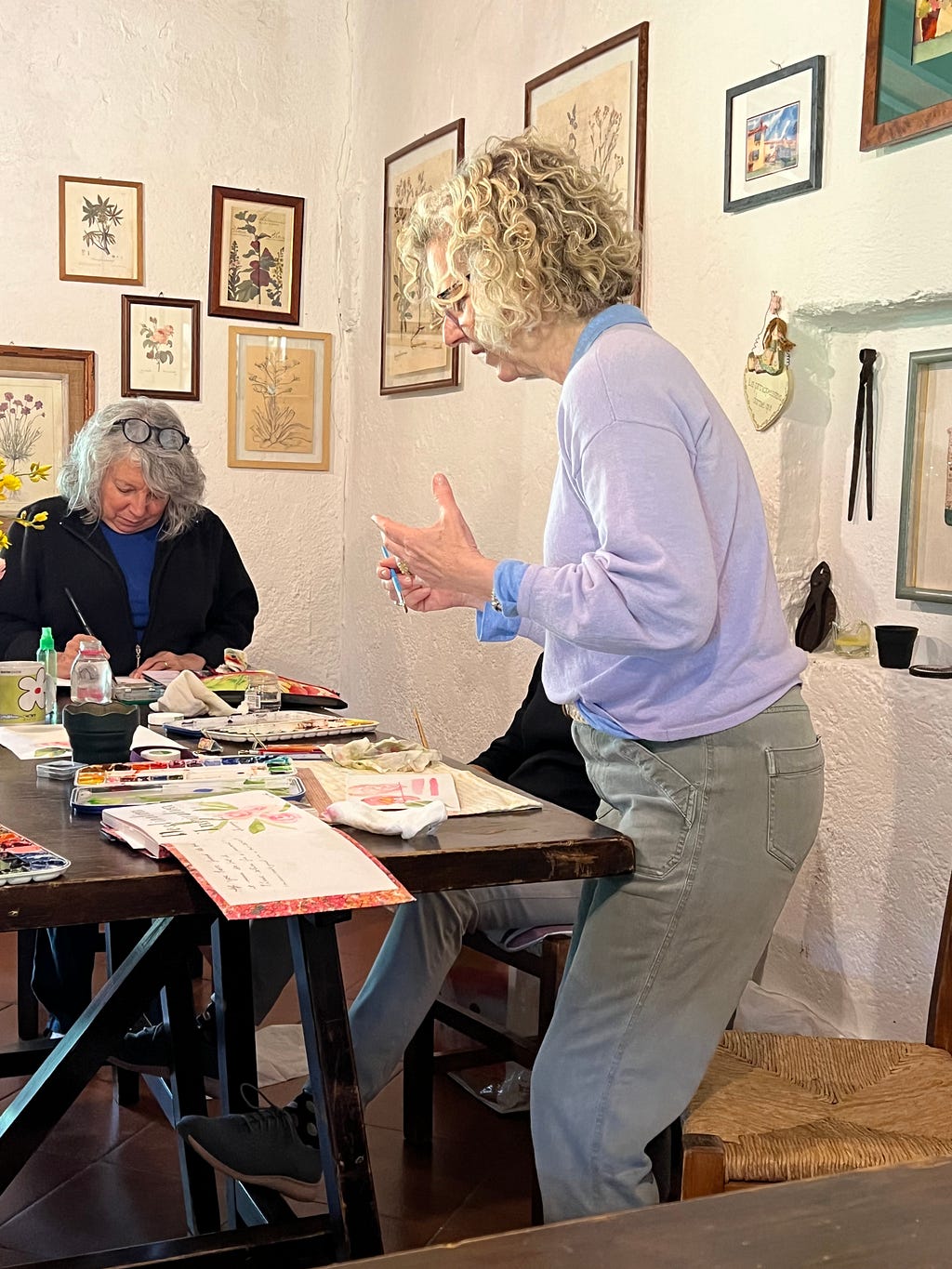 Watercolor artist Roxanne Steed, standing up to gesture with her hands about the painterliness of the watercolor craft.