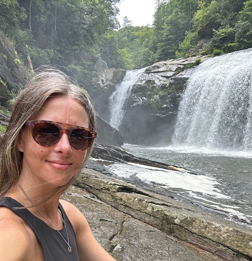 Christine smiling near a waterfall in North Carolina.