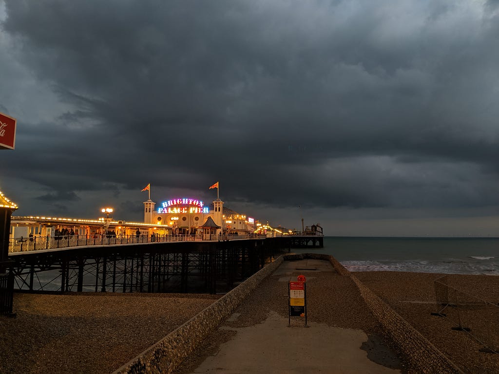 Brighton pier lit up up with dark storm clouds behind